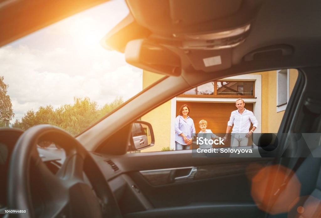 Young couple with little boy son goes to their car standing on the home yard inside car view