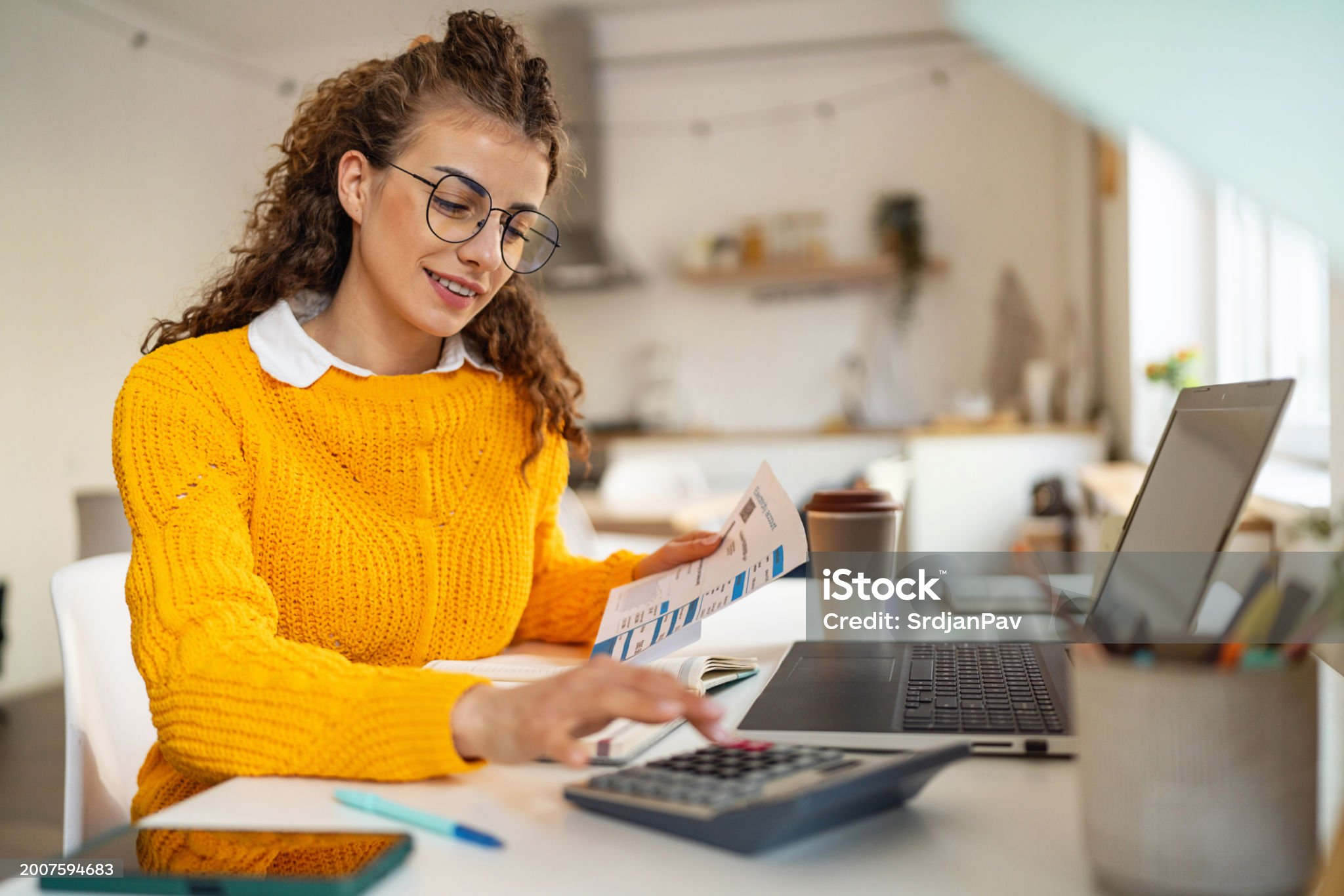 Young Caucasian woman using calculator, while organizing home finances